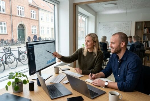 Moderne webbureau i allese med team ved computer og digitale dashboards i naturligt lys