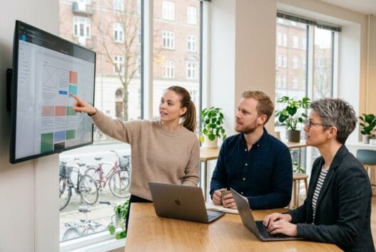 Realistisk kontorscene med dansk team, der arbejder med webdesign og digital strategi i frederiksberg