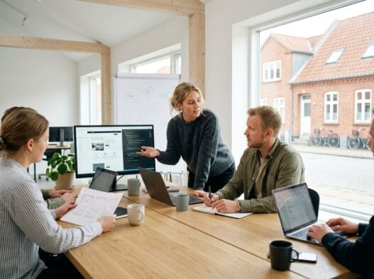 Moderne webbureau i Høng med team ved computer og dashboards i lyst kontormiljø