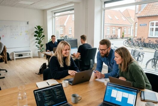 Moderne webbureau i Holløse med skandinaviske medarbejdere foran dashboards og kode på skærmen