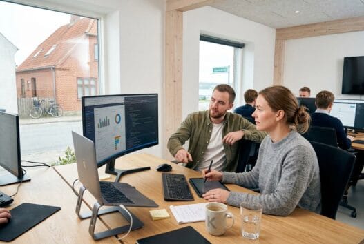 Dansk webbureau i kulhuse med team ved computer og dashboards i moderne kontormiljø