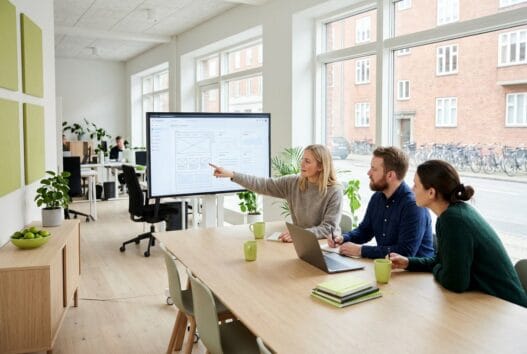 Lime webbureau med skandinavisk team foran computerskærme i et moderne kontor