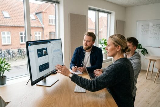 Dansk webbureau i østbirk med team ved computere og digitale dashboards i moderne kontor