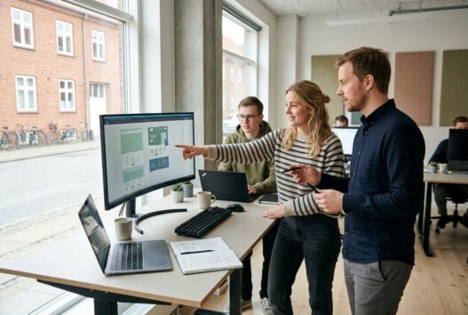 Dansk webbureau i Sønderby med team ved computer og digitale dashboards i moderne kontor